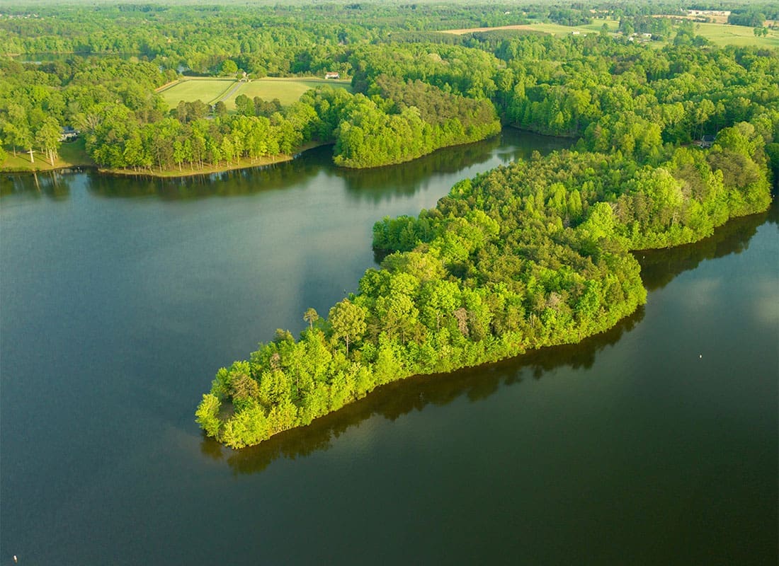 Burlington, NC - Aerial View of Land with Vibrant Green Trees Surrounded by Water in Burlington North Carolina