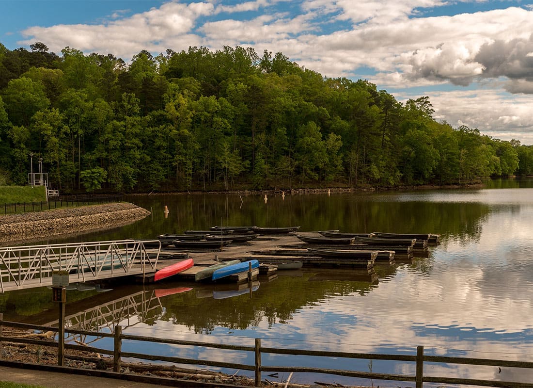 Carrboro, NC - View of Colorful Canoes on the Lake Next to a Wooden Dock in Carrboro North Carolina